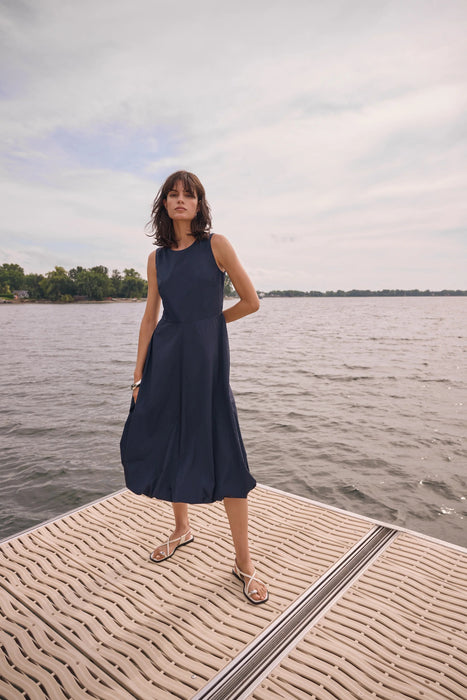 Woman wearing Joseph Ribkoff bubble skirt A-line dress, featuring a sleeveless design, midi length, voluminous hem, and a flattering elegant silhouette.