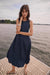 Woman wearing Joseph Ribkoff bubble skirt A-line dress, featuring a sleeveless design, midi length, voluminous hem, and a flattering elegant silhouette.