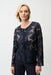 Woman wearing a dark blue zip-up mesh jacket with laser cutout leatherette details from Joseph Ribkoff