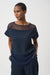 Woman wearing a dark blue textured short sleeve top with sheer mesh insert from Joseph Ribkoff