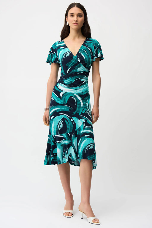 Woman wearing a green and black abstract strokes patterned dress with ruffled midi hem from Joseph Ribkoff