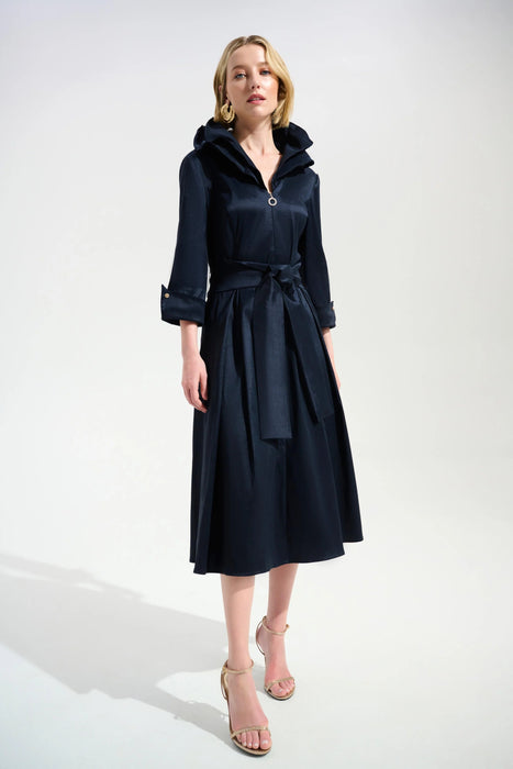 Woman wearing a dark blue pleated midi flared dress with double collar, belt, and side pockets from Joseph Ribkoff