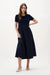 Woman wearing Joseph Ribkoff midnight blue trapeze dress with mixed fabric design styled for evening wear, events, and elegant modern occasions.