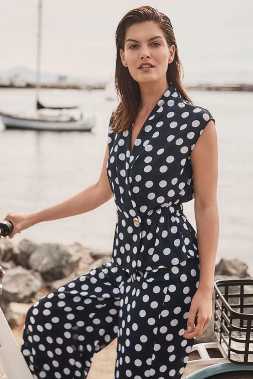 Woman wearing Joseph Ribkoff midnight blue and vanilla dot wrap peplum top styled for office chic, dinner dates, summer events, and elegant casual occasions.