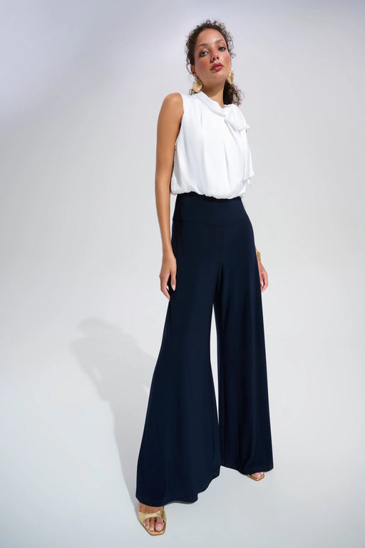 Woman wearing a two-tone one piece jumpsuit with white mock neck top and dark blue wide leg from Joseph Ribkoff