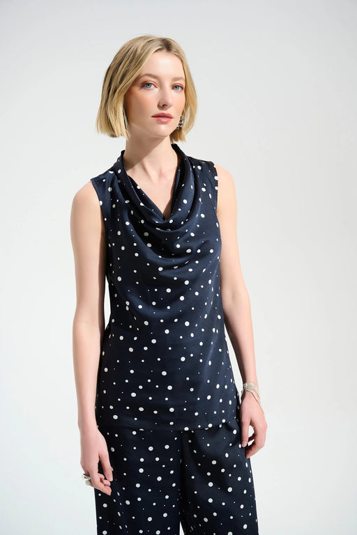 Woman wearing a dark blue sleeveless top with white polka dots and cowl neck from Joseph Ribkoff