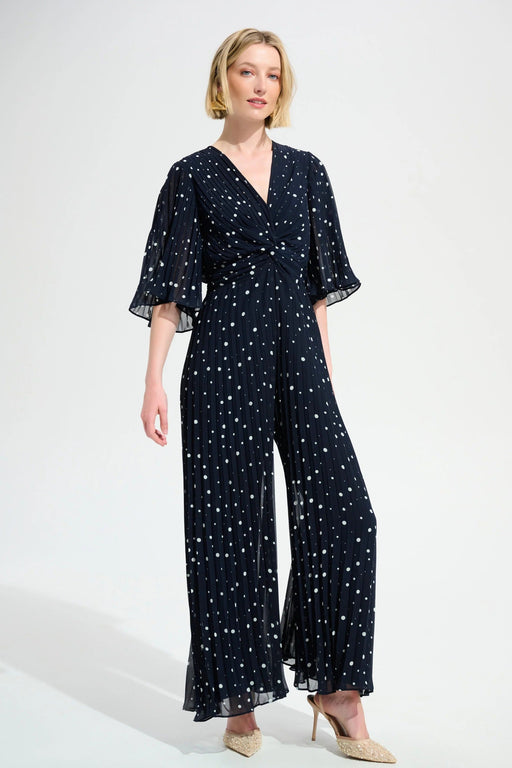 Woman wearing a navy blue jumpsuit with white polka dot pattern and wide leg from Joseph Ribkoff