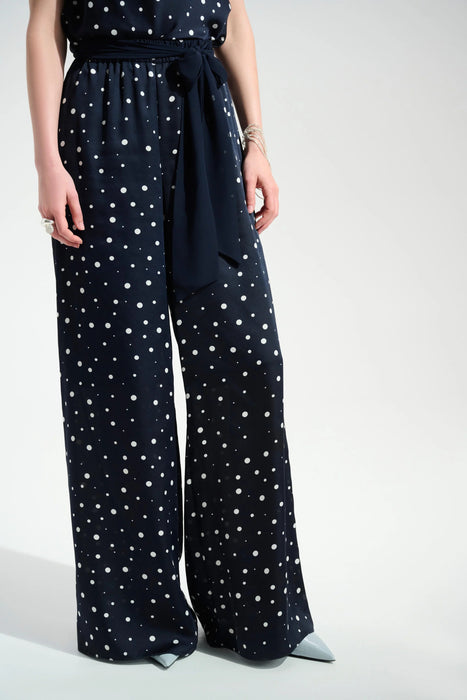 Woman wearing a dark blue wide leg pants with white polka dots and waist sash from Joseph Ribkoff