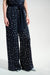 Woman wearing a dark blue wide leg pants with white polka dots and waist sash from Joseph Ribkoff