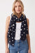 Woman wearing a navy blue scarf with white polka dots and fringe edges from Joseph Ribkoff