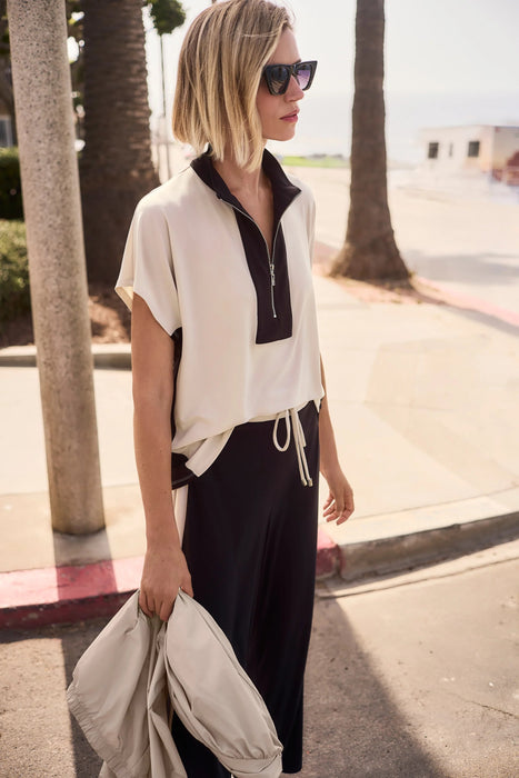 Woman wearing a beige and black two-tone color block short sleeve top with zip up front from Joseph Ribkoff