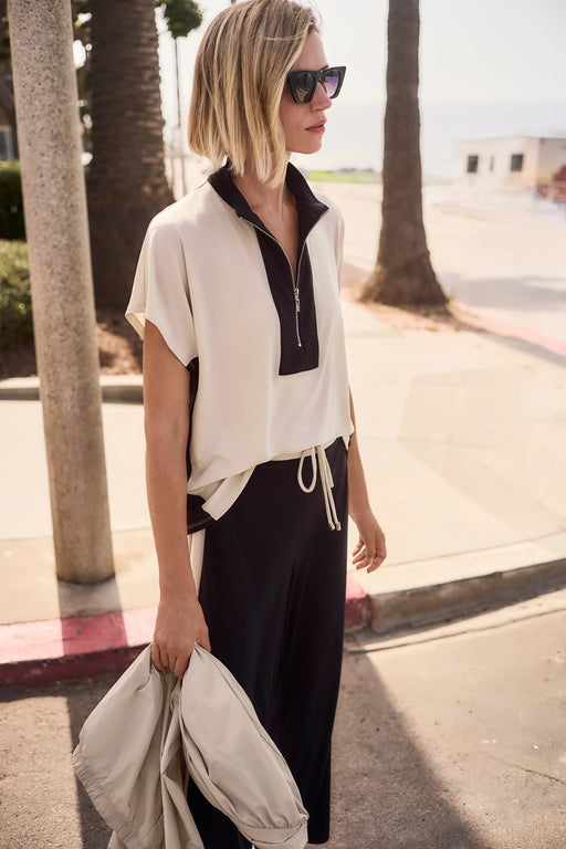 Woman wearing a beige and black two-tone color block short sleeve top with zip up front from Joseph Ribkoff