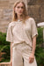 Woman wearing Joseph Ribkoff tropical print sweater with subtle shimmer styled for resort wear, casual chic outfits, and elevated everyday looks.