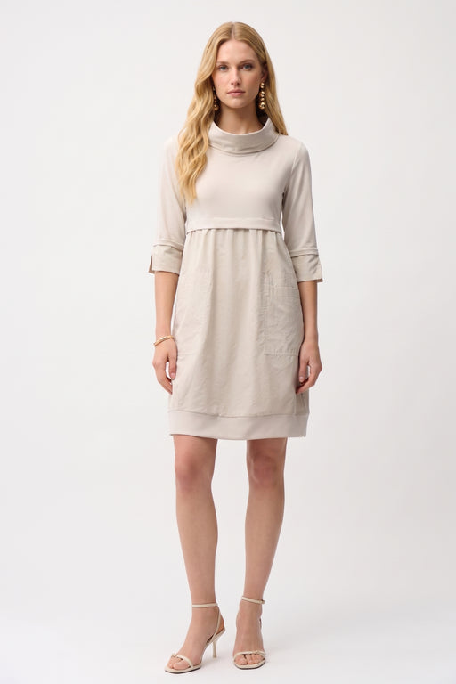 Woman wearing a knee-length cocoon dress with a cowl neckline, patch pockets, and fold-back cuff sleeves, styled for office wear, travel, or casual elegant occasions.