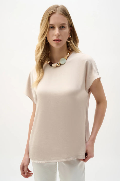 Woman wearing a beige satin top with crew neck and short sleeves from Joseph Ribkoff