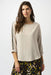 Woman wearing a beige lightweight blouse with contrasting rhinestone embellishments on the 3/4 sleeves