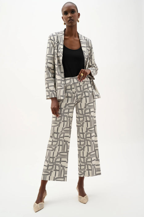Woman wearing Joseph Ribkoff geometric print wide leg pants, featuring a high-waisted fit, cropped length, bold abstract pattern, and a relaxed modern silhouette.