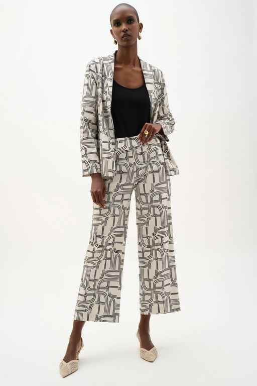 Woman wearing Joseph Ribkoff geometric print wide leg pants, featuring a high-waisted fit, cropped length, bold abstract pattern, and a relaxed modern silhouette.