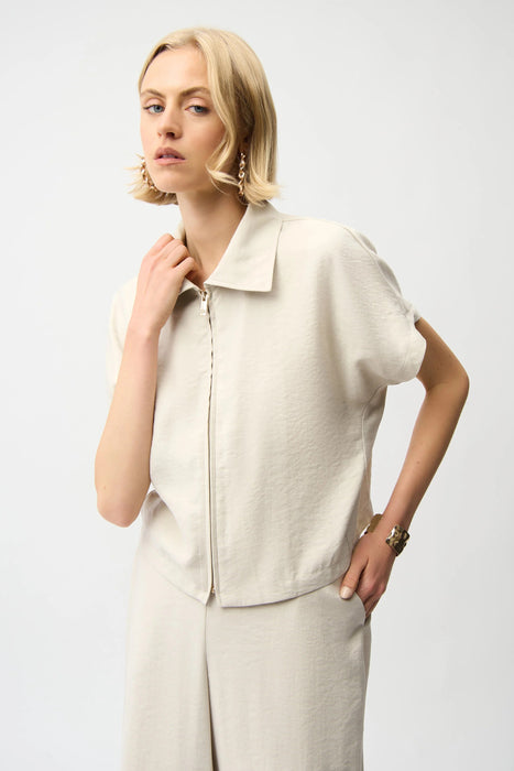 Woman wearing a moonstone woven boxy jacket with front zipper and structured collar, styled with matching neutral outfit.