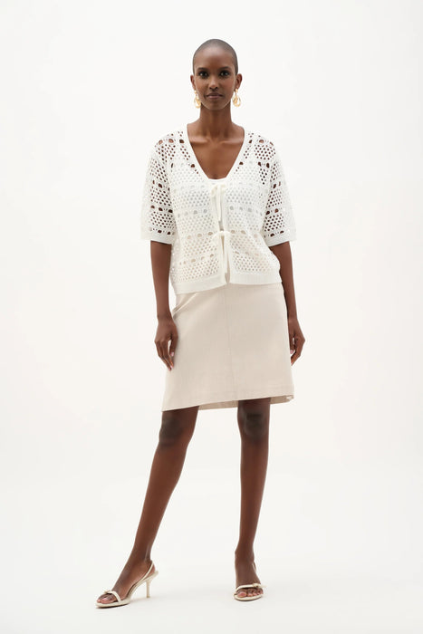 Woman wearing Joseph Ribkoff natural A-line skirt with side pockets, featuring a knee-length cut, clean minimalist design, and a flattering tailored silhouette.