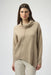 Woman wearing a solid color beige sweater knit top with cowl neck and asymmetric hem