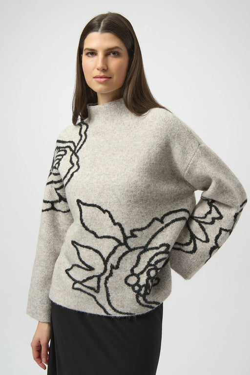 Woman wearing a light gray sweater with black floral pattern and mock neckline