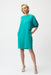Woman wearing a turquoise shift dress with puff sleeves, zip front and side pockets from Joseph Ribkoff
