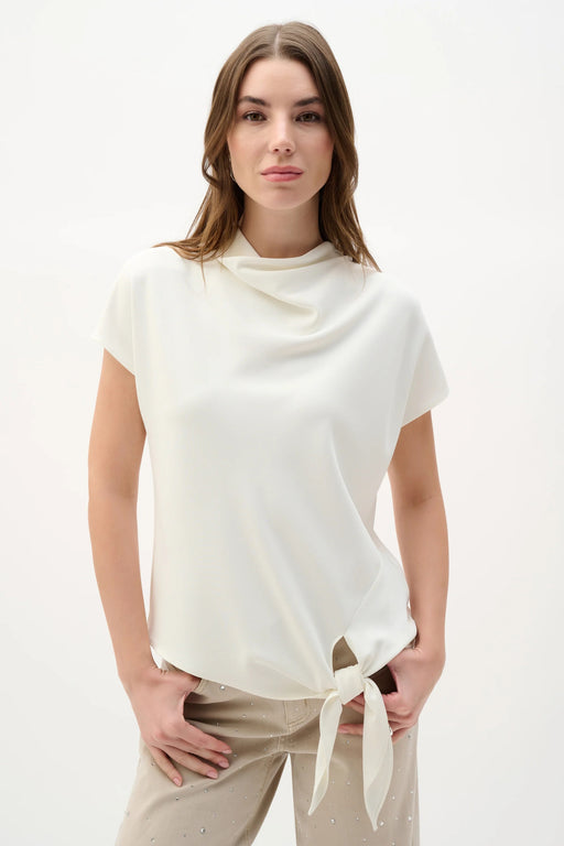 Woman wearing Joseph Ribkoff off-white cowl neck boxy top with knotted hem styled for office chic, casual outings, travel, and modern elegant wear.