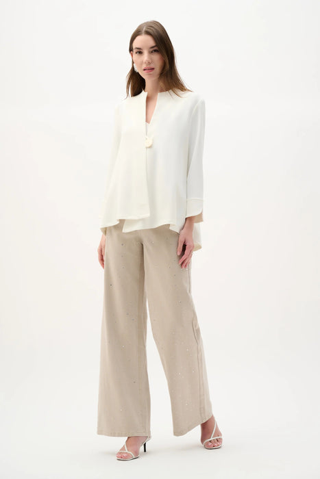 Woman wearing Joseph Ribkoff off-white swing jacket with statement button, featuring a flowy silhouette, lightweight fabric, elegant drape, and a modern flattering fit.