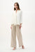Woman wearing Joseph Ribkoff off-white swing jacket with statement button, featuring a flowy silhouette, lightweight fabric, elegant drape, and a modern flattering fit.