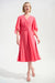 Woman wearing a pink knee-length dress with surplice neck and flutter chiffon sleeves from Joseph Ribkoff