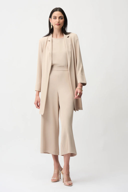 Woman wearing a parchment longline blazer with notched collar and open front, styled with a matching minimalist outfit.