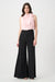 Woman wearing a two-tone one piece jumpsuit with pink mock neck top and black wide leg from Joseph Ribkoff