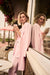 Woman wearing an open front pink coat with fringe trim and long sleeves from Joseph Ribkoff