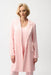 Woman wearing an open front pink coat with fringe trim and long sleeves from Joseph Ribkoff