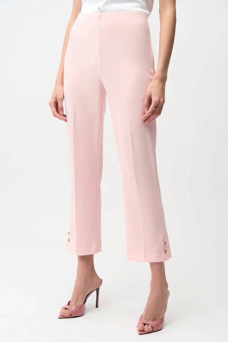 Woman wearing a light pink cropped high waist pants with gold rose buttons at the hem from Joseph Ribkoff