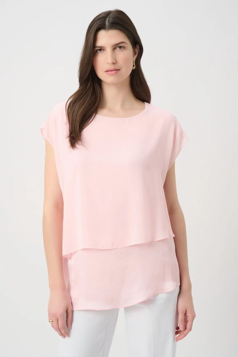 Woman wearing a light pink layered tunic top with asymmetric hem and short sleeves from Joseph Ribkoff
