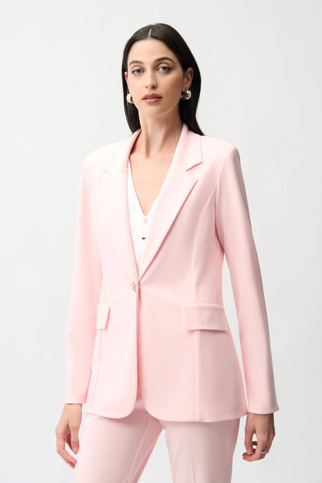 Woman wearing a light pink fitted blazer jacket with flap pockets and gold rose button from Joseph Ribkoff