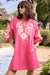 Woman wearing a pink sherbet straight dress with canvas floral embroidery, long sleeves, and a relaxed fit, styled outdoors near a pool.