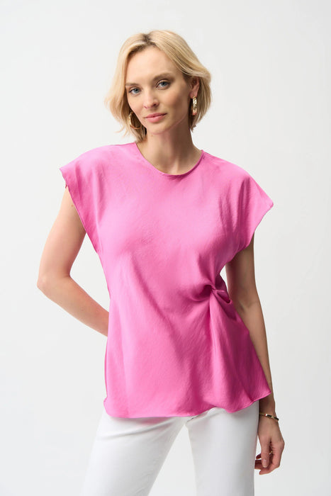 Woman wearing a pink satin top with twist front detail and dolman sleeves from Joseph Ribkoff