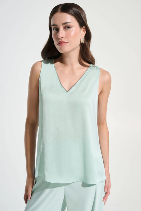 Woman wearing a light green sleeveless top with rhinestone trim v-neck from Joseph Ribkoff