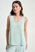 Woman wearing a light green sleeveless top with rhinestone trim v-neck from Joseph Ribkoff