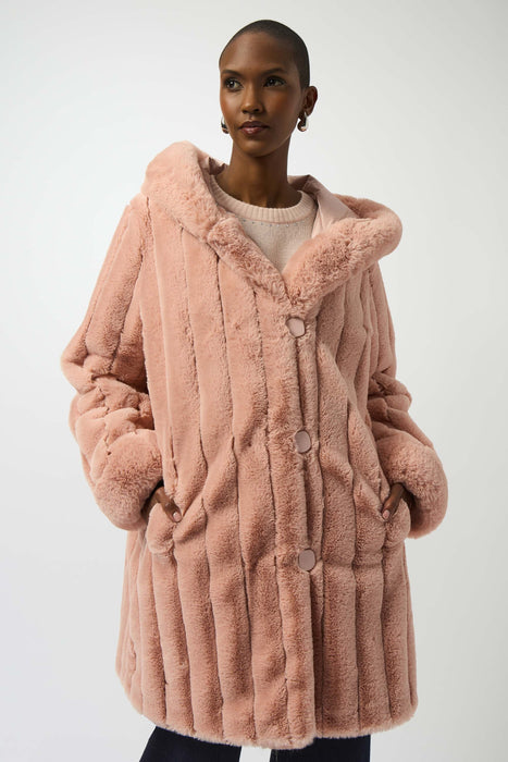 Woman wearing a pink reversible hooded quilted faux fur coat
