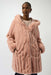 Woman wearing a pink reversible hooded quilted faux fur coat