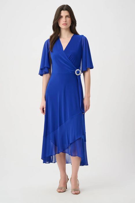 Woman wearing a blue dress with wrap neck and ruffle hem from Joseph Ribkoff