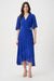 Woman wearing a blue dress with wrap neck and ruffle hem from Joseph Ribkoff