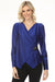 Woman wearing a blue wrap-style blouse with ornament at the waist and long sleeves from Joseph Ribkoff