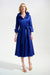 Woman wearing a royal blue pleated midi flared dress with double collar, belt, and side pockets from Joseph Ribkoff