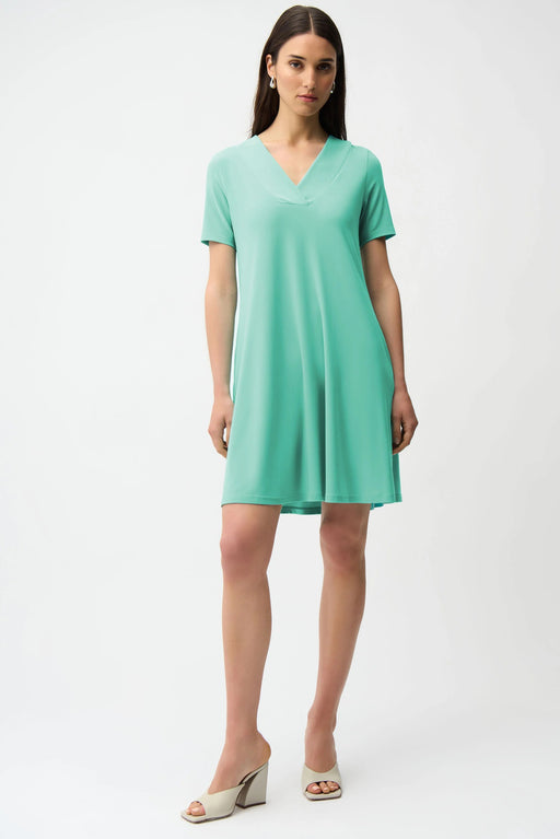 Woman wearing Joseph Ribkoff seafoam overlapping V-neckline A-line dress, featuring a soft flowy silhouette, short sleeves, and a flattering knee-length fit.