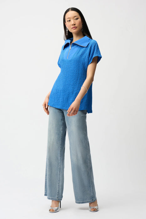 Woman wearing Joseph Ribkoff seersucker boxy top with memory collar, featuring a textured fabric, zip neckline, short sleeves, and a relaxed modern fit.